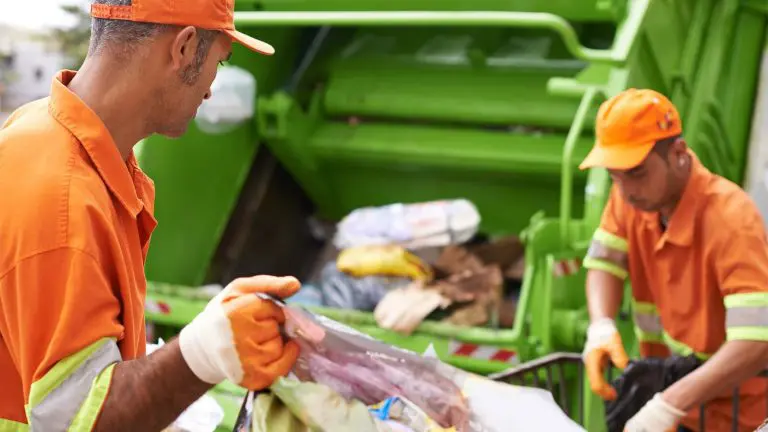 Recolección de basura – Servicio La imagen muestra a dos personas de servicio de recolección de basura subiendo la misma a un camión de recolecta