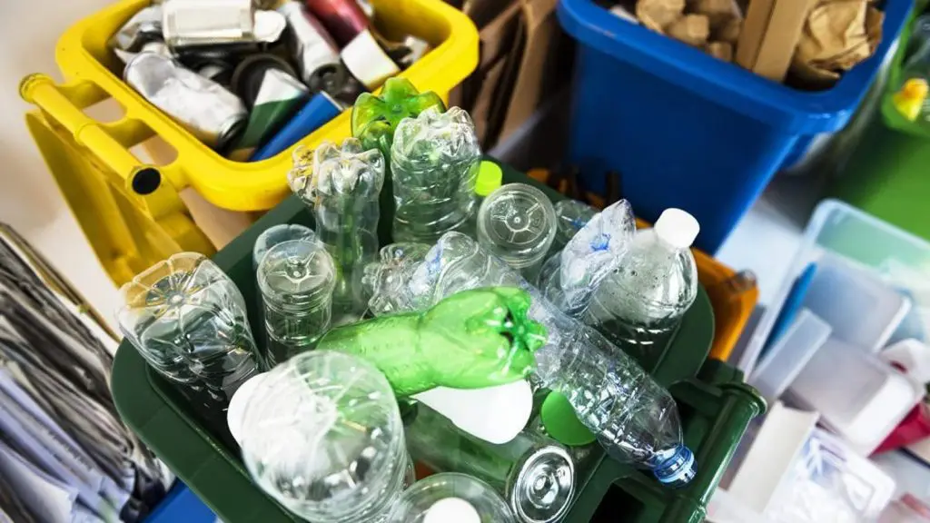 Contenedores llenos de botellas de plástico y otros objetos reciclables.
